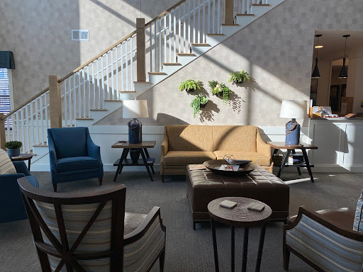 A cozy living room setup featuring a mix of modern and classic furniture, illuminated by natural light.