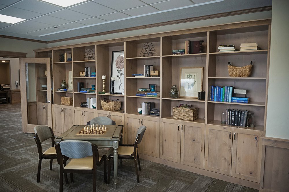 A cozy office space with a wooden bookshelf and a chess table.