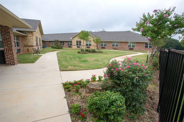 A well-maintained garden with pathways leading to a brick building.