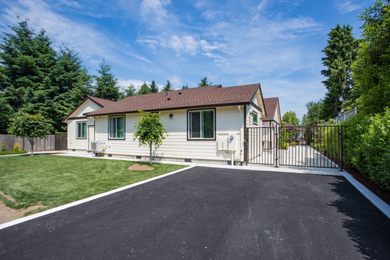 A suburban house with a gated driveway and lush lawn.
