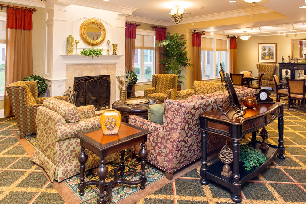 A cozy living room with patterned sofas, armchairs, a fireplace, and decorative elements.