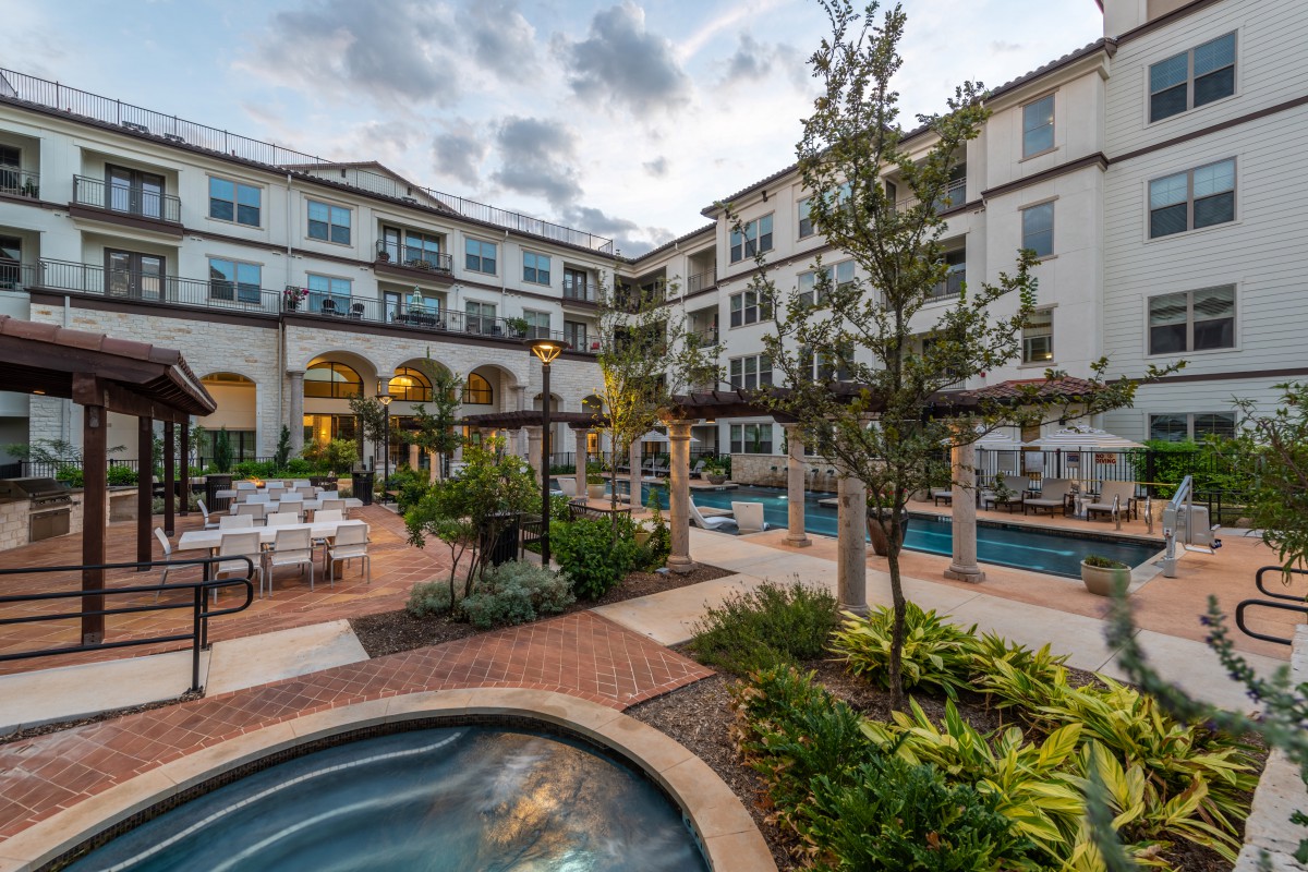 A scenic courtyard in a modern residential building with lush landscaping and outdoor seating areas.