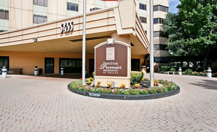 Entrance of a hotel with signage and well-maintained landscaping.