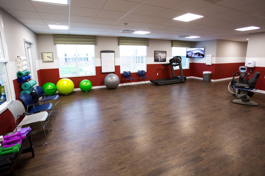 An exercise room with fitness equipment including a treadmill and yoga balls.