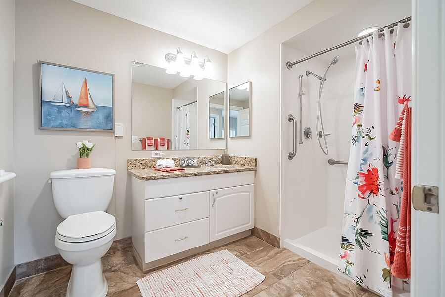A clean and bright bathroom with a shower, toilet, sink, and decorative elements.