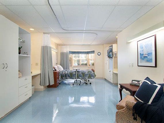 A clean and well-organized hospital room with a patient bed and furniture.