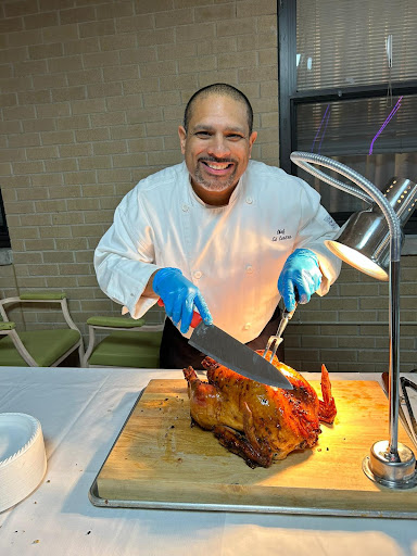 A chef joyfully carving roasted meat in a professional kitchen setting.