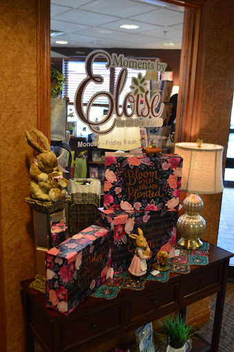 A charming display featuring Eloise-themed decor and colorful gift boxes, complemented by decorative figurines and a warm lamp.