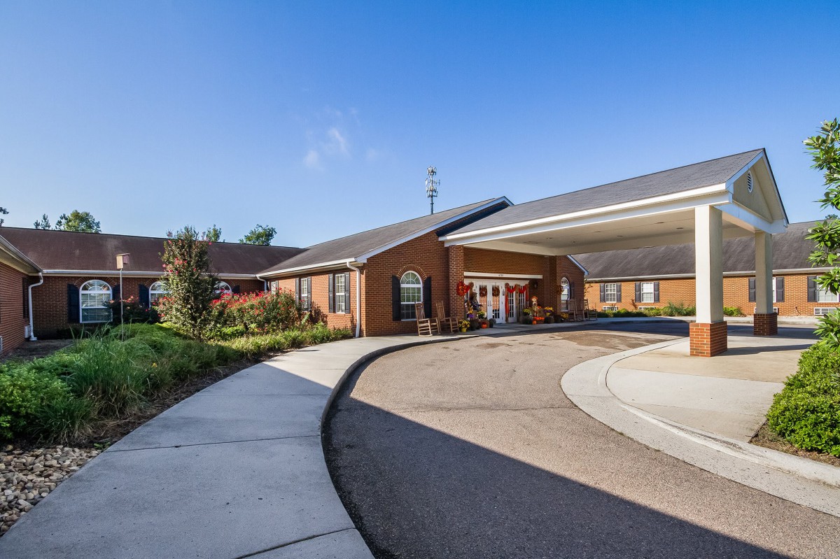 A building with a driveway and landscaped entrance under a clear blue sky.