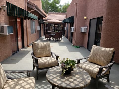A cozy outdoor patio with comfortable seating and a small table, set between two buildings.