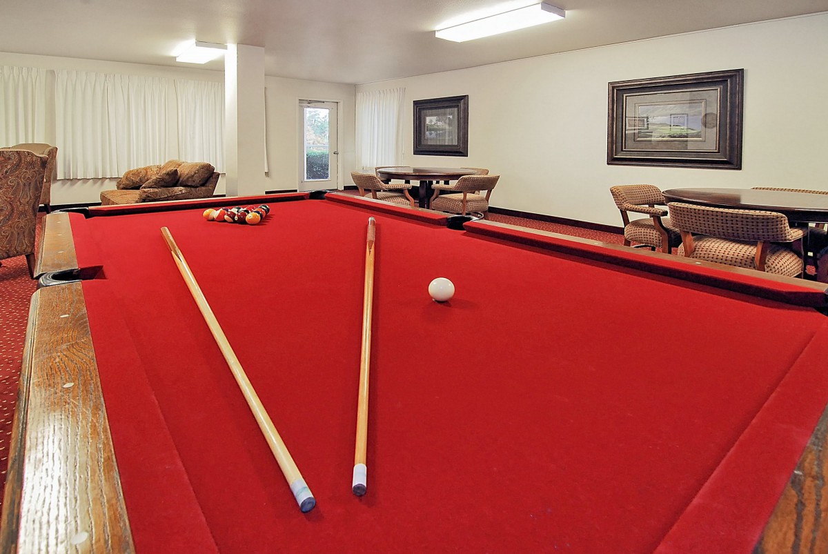 A cozy game room featuring a red-felt pool table and comfortable seating.