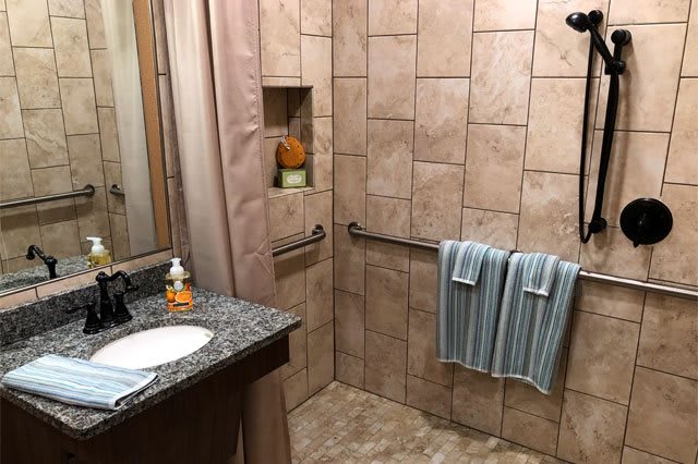 A neatly arranged bathroom with beige tiled walls, a granite countertop sink, and blue-striped towels.