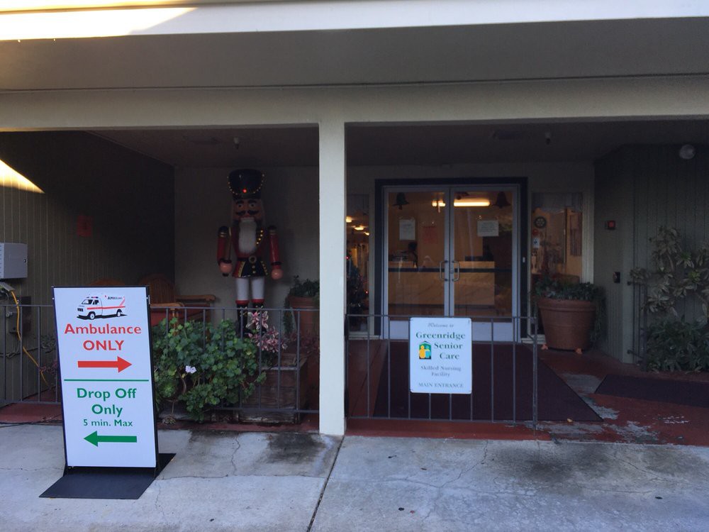 The entrance to a building with holiday decorations and directional signs.