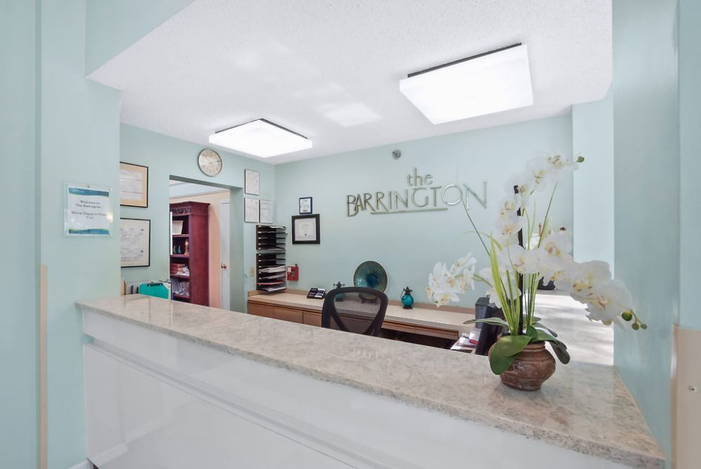 A tidy reception area with a desk, decorative flowers, and office supplies.
