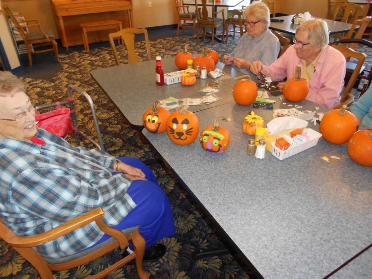A group of people participating in a pumpkin carving activity indoors.