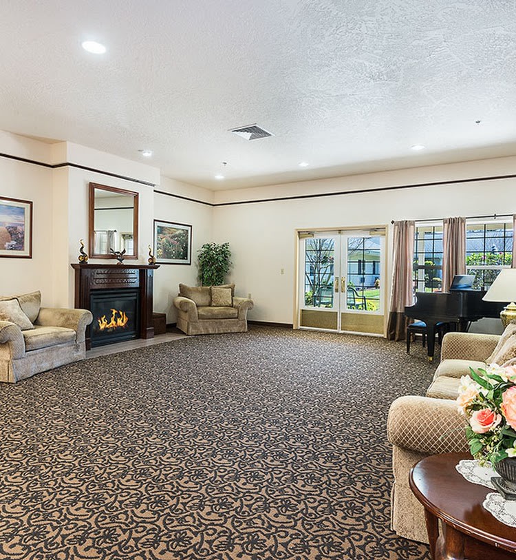 A spacious living room with comfortable seating, a fireplace, and a grand piano.