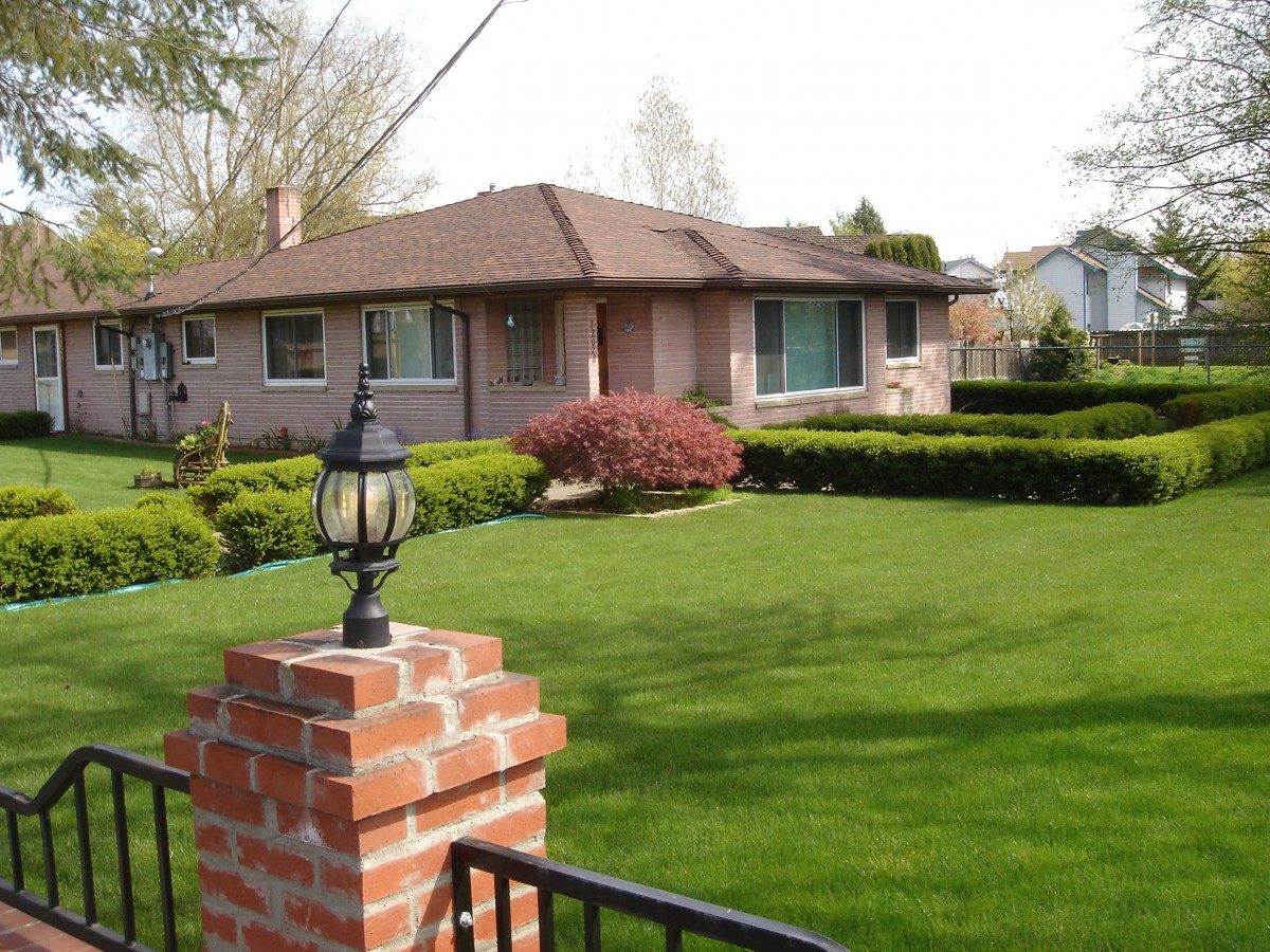 A suburban brick house with a well-maintained lawn and garden.