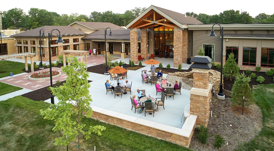 A modern building with an outdoor patio area featuring tables and chairs occupied by people enjoying the space.