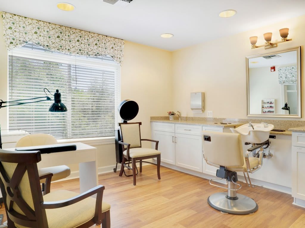 A cozy and well-lit hair salon interior with styling chairs, a mirror, and a window providing natural light.