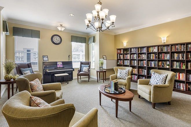 A cozy living room with a piano, bookshelves, and comfortable seating.