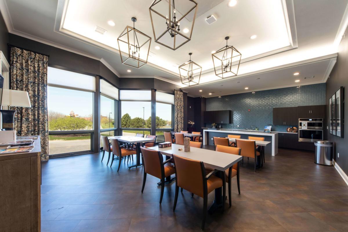 A modern dining area with stylish lighting and ample natural light streaming through large windows.