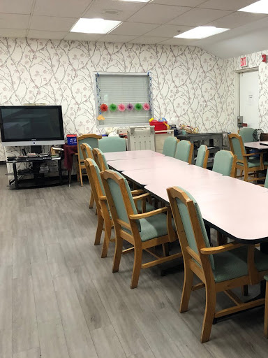 A spacious meeting room equipped with a long table and comfortable chairs, featuring a television and decorative wallpaper.