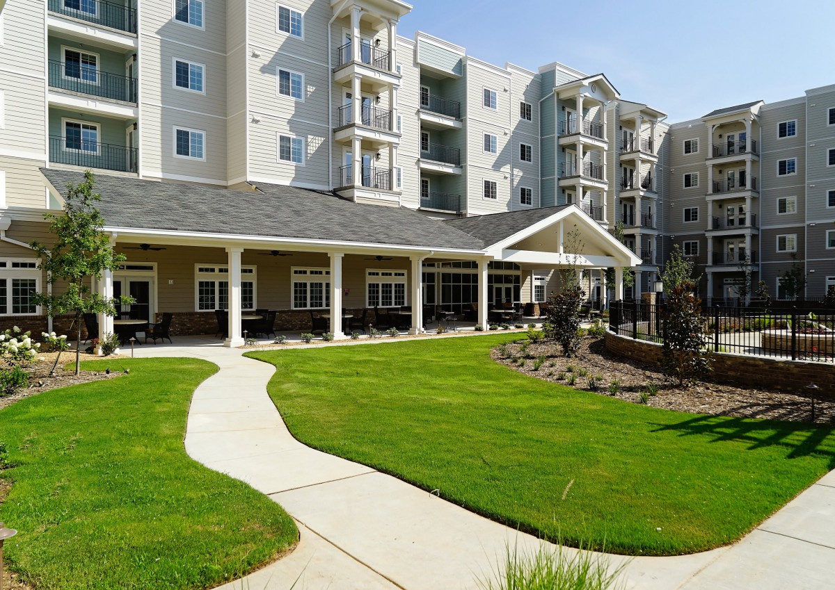 A modern residential apartment building with well-maintained landscaping and a neatly manicured lawn.