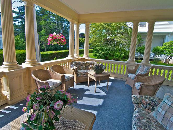 A cozy porch with wicker furniture and lush greenery, perfect for relaxing outdoors.