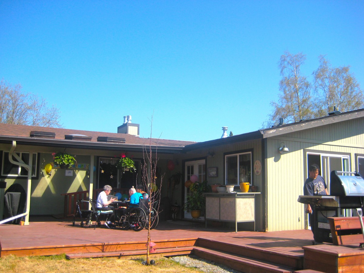 A sunny day at an outdoor cafe with people sitting on a wooden deck.