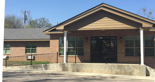 A modern single-story brick building with large windows, featuring a welcoming entrance.