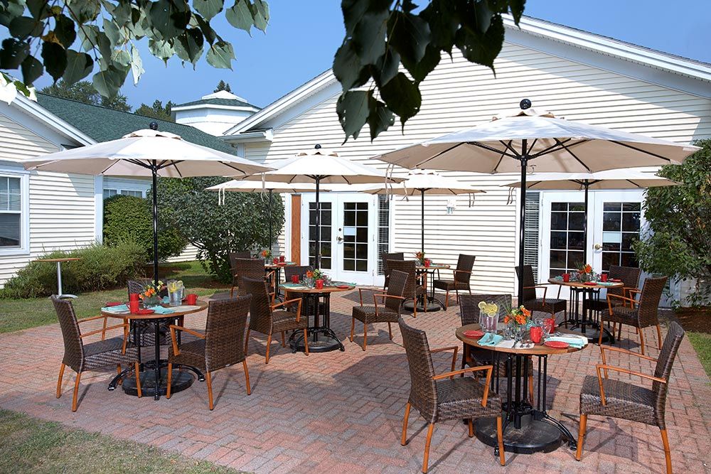 A charming outdoor restaurant patio with umbrellas and neatly arranged tables and chairs under a sunny sky.