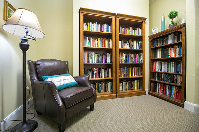 A cozy reading room with bookshelves filled with books and a comfortable leather chair.
