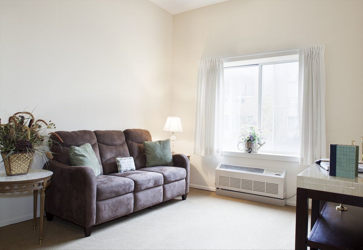 A cozy living room with a sofa, lamp, and large window.