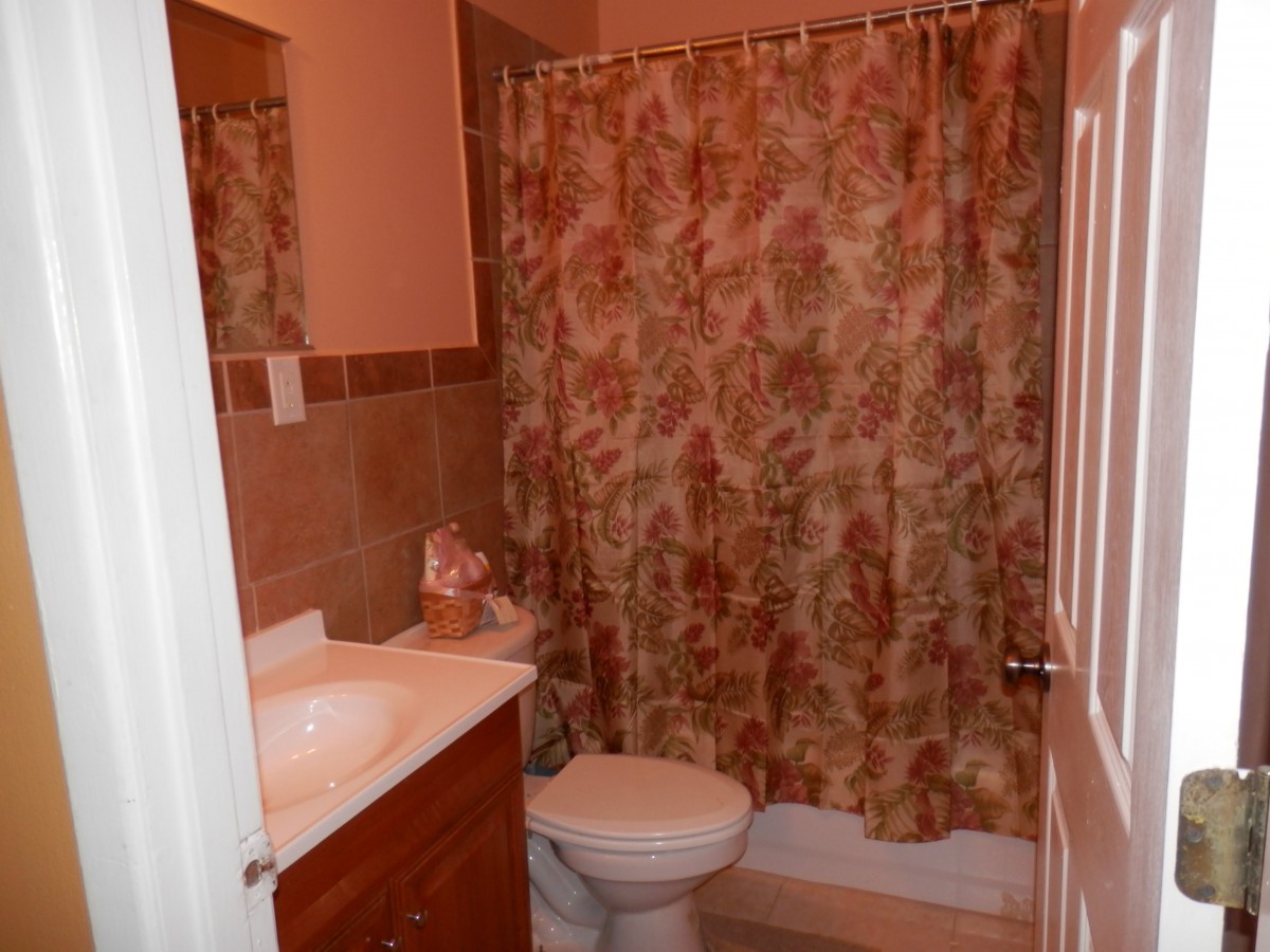 A compact bathroom featuring a sink, toilet, and floral-patterned shower curtain.