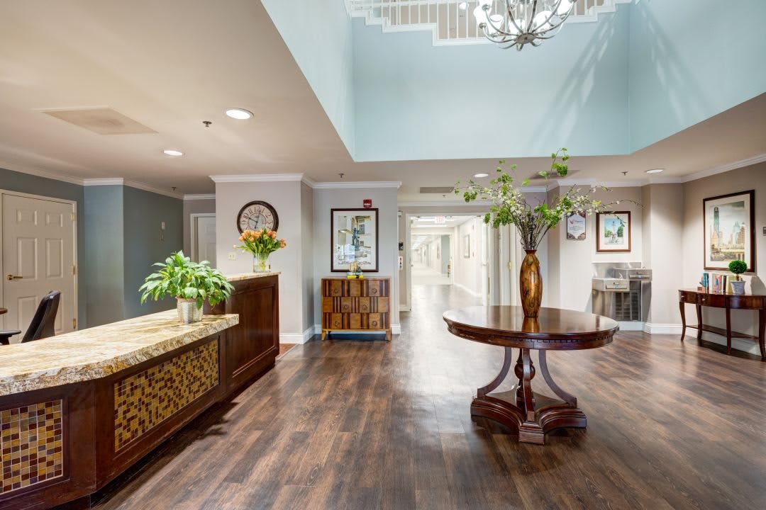 A stylish and elegant lobby interior featuring wooden flooring, decorative furniture, and a chandelier.