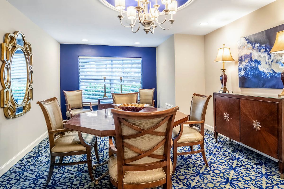 A well-decorated dining room featuring a wooden table and chairs, a chandelier, and elegant carpeting.