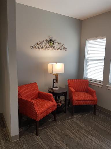 A cozy corner featuring two orange armchairs and a lamp, perfect for relaxation.