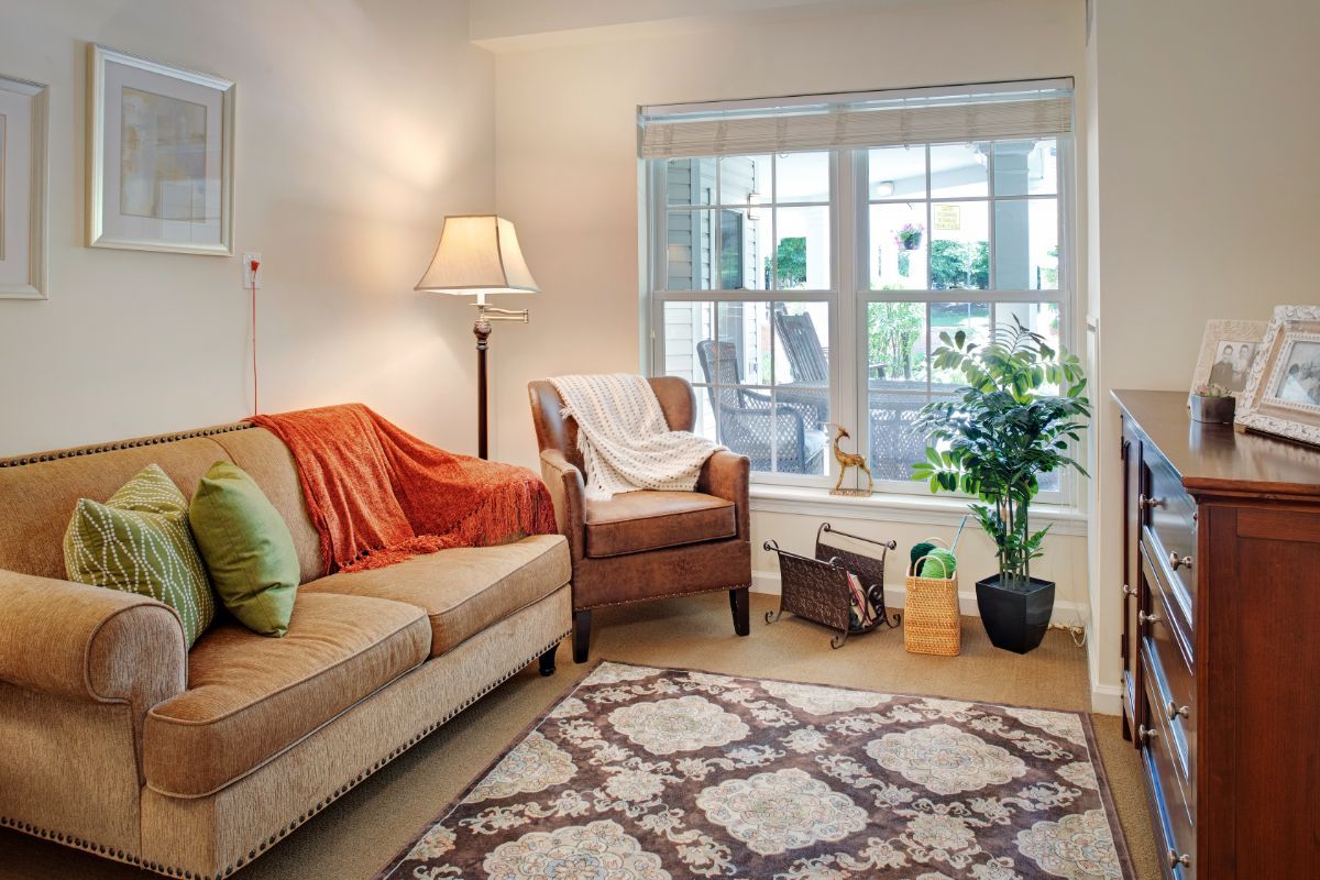 A cozy living room with a sofa, armchair, and a large window.