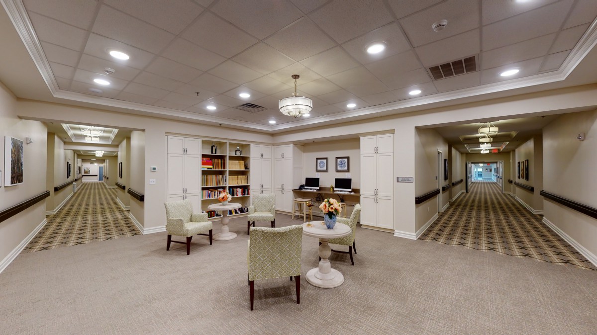 A cozy seating area with bookshelves and computers in a well-lit room.