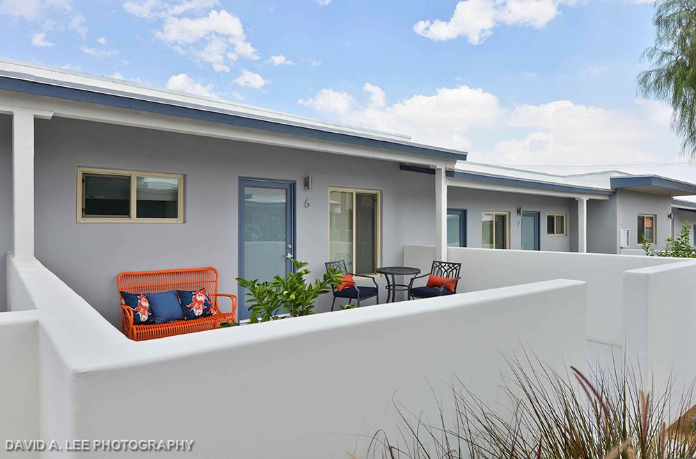 A modern outdoor patio featuring seating and a small table alongside a building with a minimalist design.