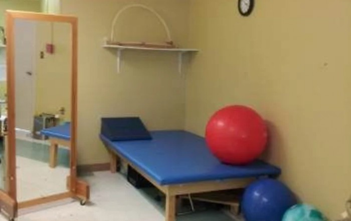 A physical therapy room featuring a blue treatment table and exercise balls.