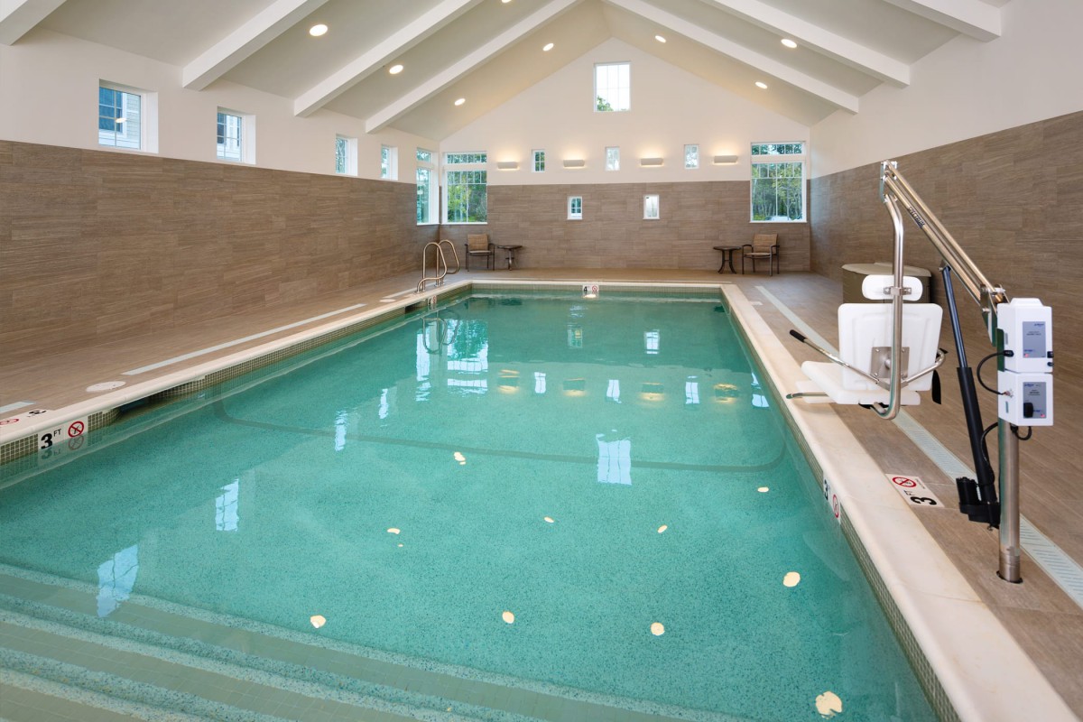 A modern indoor swimming pool with bright overhead lighting and a sleek design.