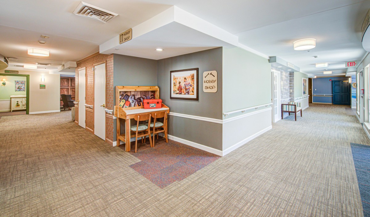 A hallway featuring a small piano and framed artwork on the walls.