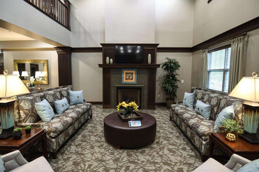 A cozy living room with a fireplace, two patterned couches, and a round coffee table.