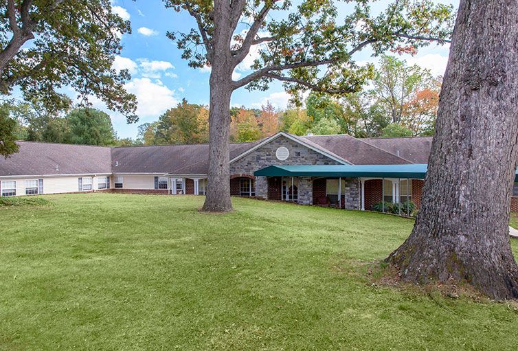 A scenic view of a building surrounded by trees and green grass.