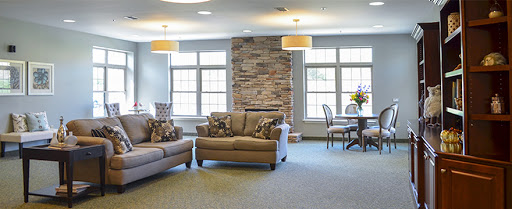 A cozy living room setup featuring comfortable couches, a dining area, and natural light from large windows.