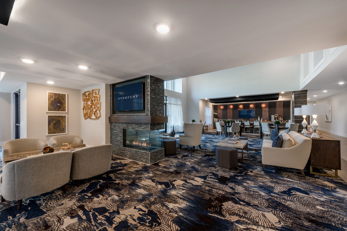 A modern lounge area featuring comfortable seating, a central fireplace, and a television.