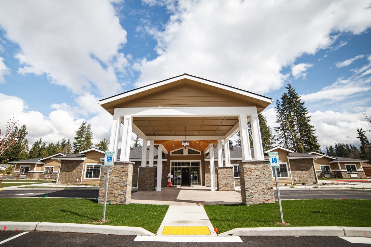 A building with a prominent entrance featuring columns and a peaked roof under a partly cloudy sky.