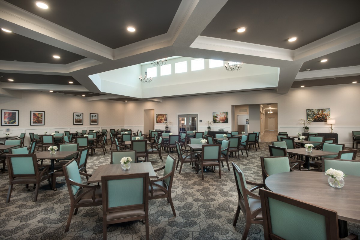 A spacious dining area with neatly arranged tables and chairs under warm lighting.