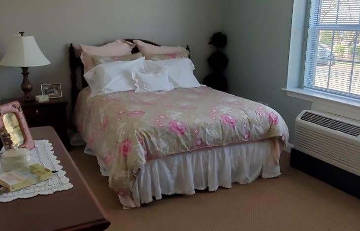 A cozy bedroom with a neatly made bed and floral bedding.